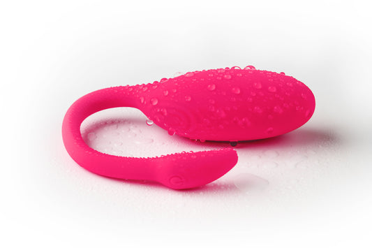 Pink wearable vibrator with water droplets on a white background.