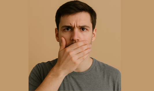 Man covering his mouth against a beige background.