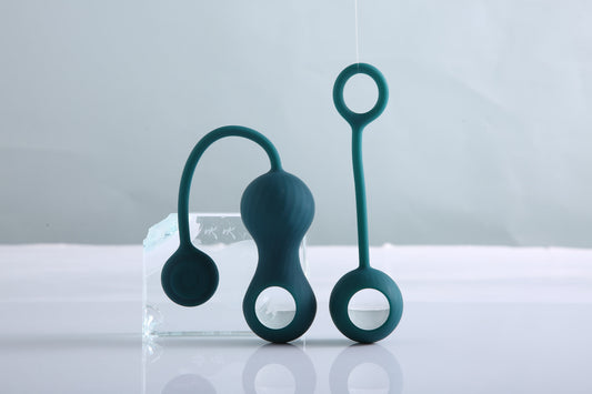 Three green Kegel training devices displayed beside a clear acrylic block.