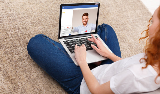 Woman using a laptop for a video call with a man on screen.
