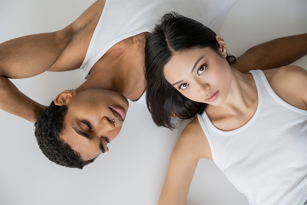 Couple lying side by side in white tops.