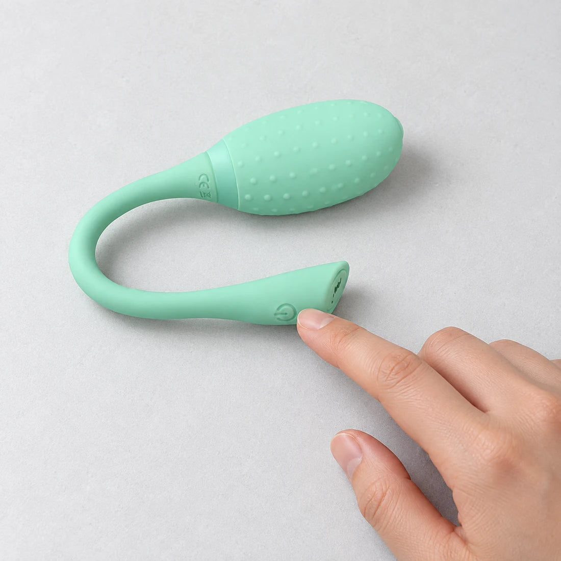 Hand touching the side button at the end of a mint green Magic Fugu tail
